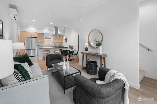 living room with sink, an AC wall unit, and light wood-type flooring