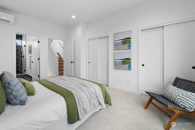 bedroom featuring multiple closets, a wall mounted AC, and light colored carpet