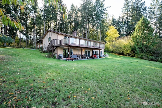 back of property with a wooden deck and a yard