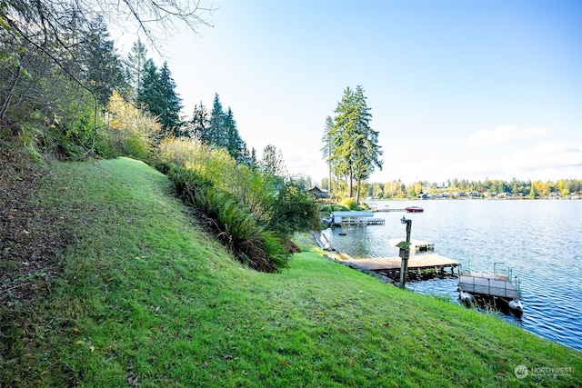 view of dock with a water view and a yard