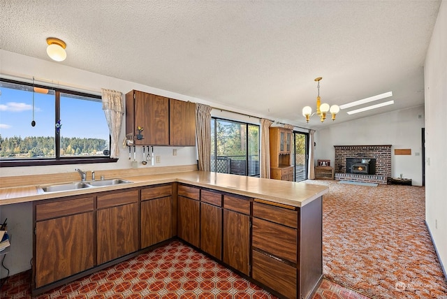 kitchen featuring plenty of natural light, decorative light fixtures, kitchen peninsula, and sink