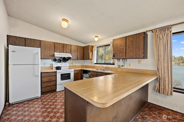 kitchen featuring sink, vaulted ceiling, a textured ceiling, kitchen peninsula, and white appliances