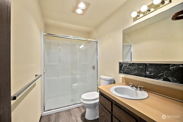 bathroom featuring a shower with door, vanity, hardwood / wood-style flooring, and toilet