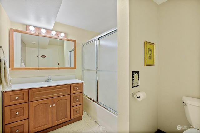 full bathroom with vanity, tile patterned floors, combined bath / shower with glass door, and toilet