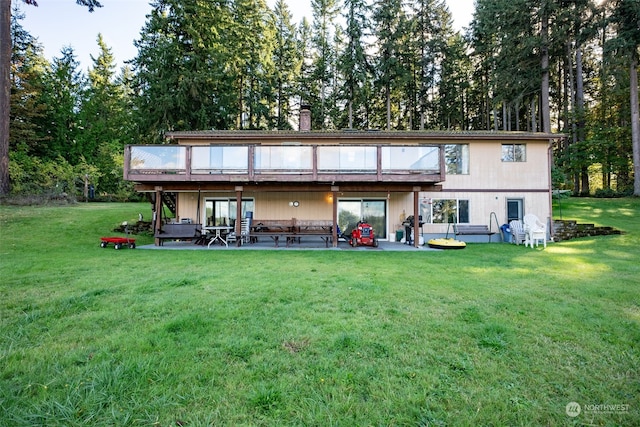 rear view of property with a patio area, a deck, and a lawn