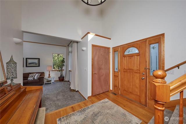 foyer entrance with a towering ceiling and light wood-type flooring