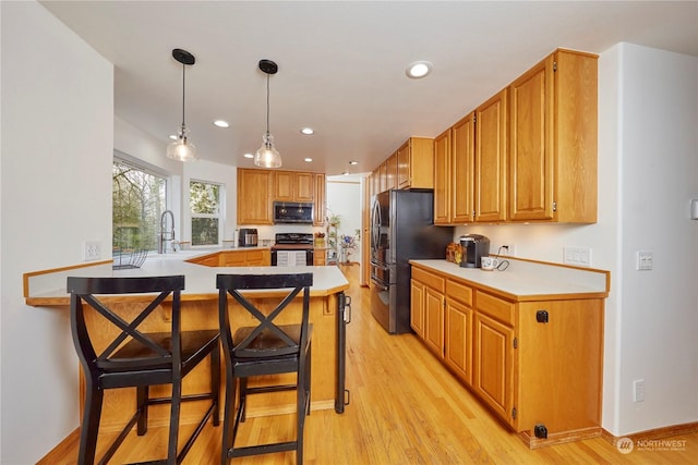 kitchen with a kitchen breakfast bar, range, kitchen peninsula, and light hardwood / wood-style flooring