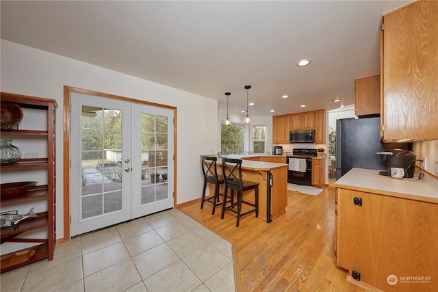 kitchen featuring range with electric stovetop, stainless steel fridge, a kitchen breakfast bar, hanging light fixtures, and kitchen peninsula