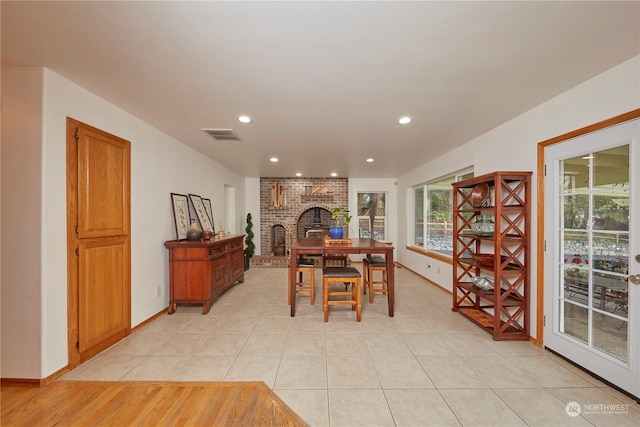 dining space with a brick fireplace and light tile patterned floors