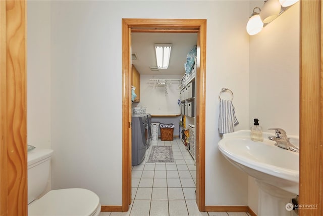 bathroom featuring tile patterned flooring, sink, toilet, and washing machine and clothes dryer