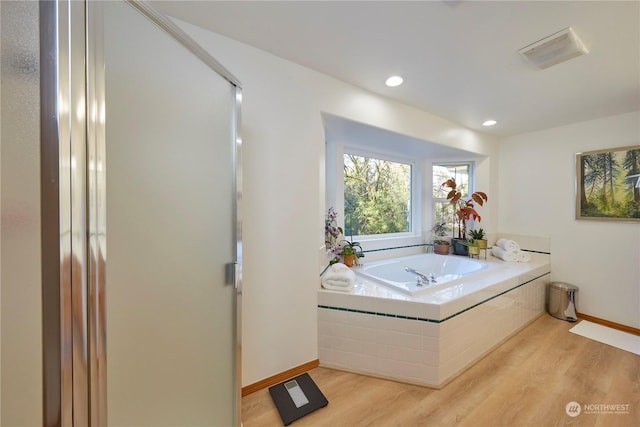 bathroom with hardwood / wood-style floors and tiled bath