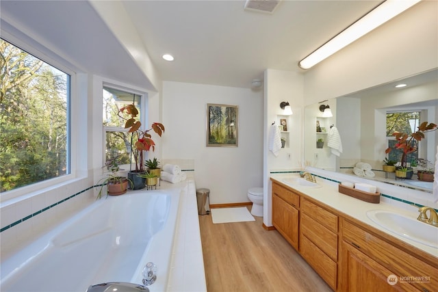 bathroom featuring vanity, a bath, hardwood / wood-style flooring, and toilet