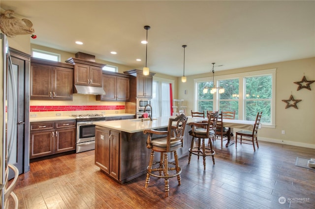 kitchen featuring a kitchen bar, sink, an island with sink, pendant lighting, and stainless steel appliances