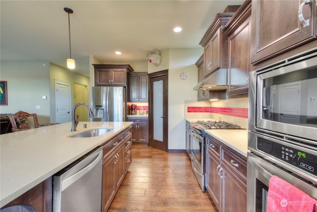 kitchen with hardwood / wood-style floors, pendant lighting, sink, backsplash, and stainless steel appliances