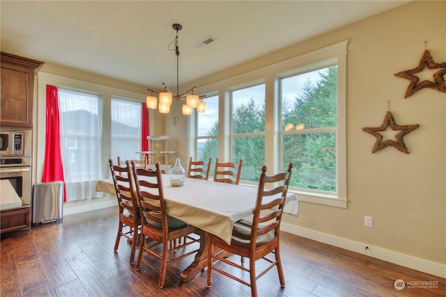 dining space featuring plenty of natural light, an inviting chandelier, and dark hardwood / wood-style flooring