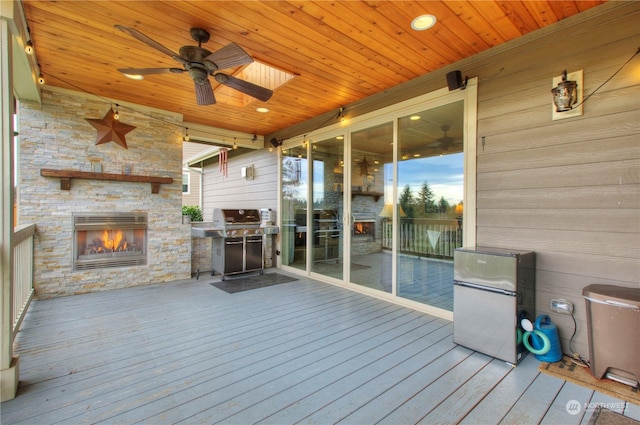 wooden deck with ceiling fan, a grill, and an outdoor stone fireplace