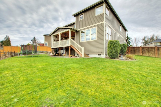 rear view of property featuring a trampoline and a yard