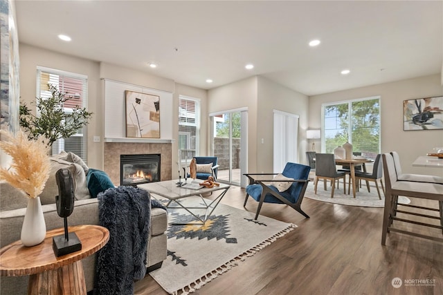 living room featuring a healthy amount of sunlight, dark hardwood / wood-style floors, and a tile fireplace