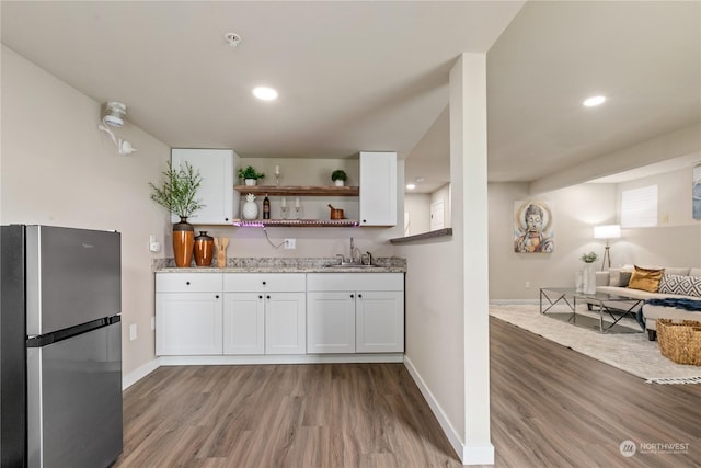 kitchen featuring stainless steel refrigerator, white cabinetry, sink, and hardwood / wood-style flooring