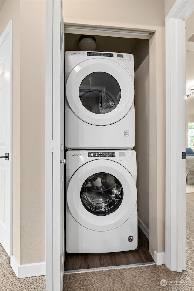 clothes washing area with stacked washer and dryer and dark carpet