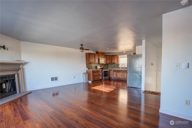 unfurnished living room with sink, dark hardwood / wood-style floors, and ceiling fan