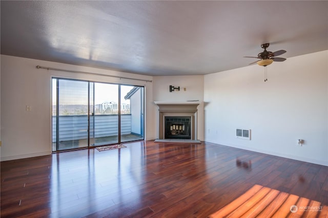 unfurnished living room featuring dark wood-type flooring and ceiling fan