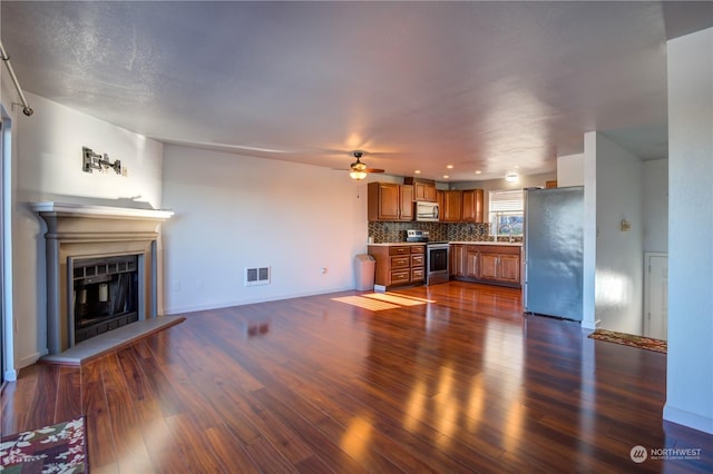 unfurnished living room with dark hardwood / wood-style flooring, sink, and ceiling fan