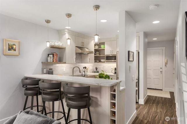 kitchen featuring decorative light fixtures, decorative backsplash, a breakfast bar, and kitchen peninsula