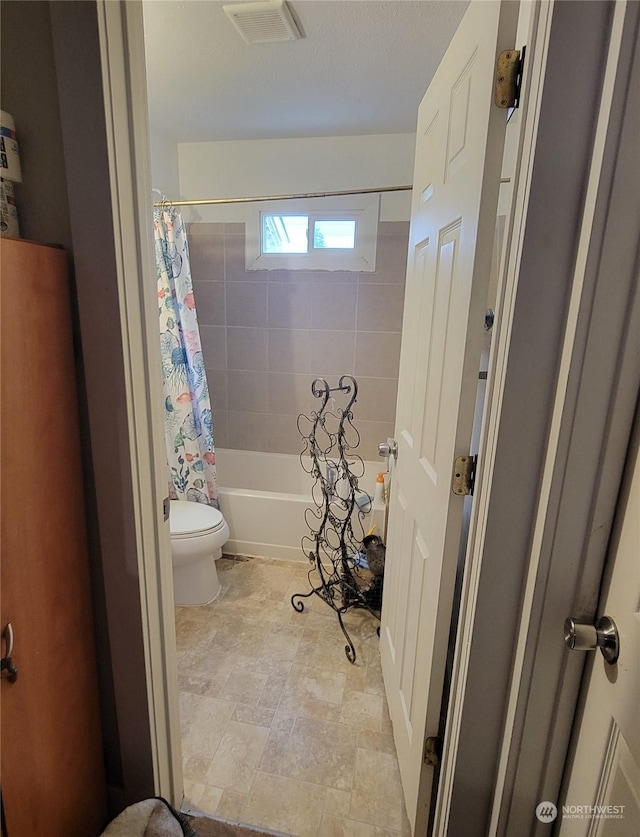 bathroom featuring toilet and shower / bath combo with shower curtain