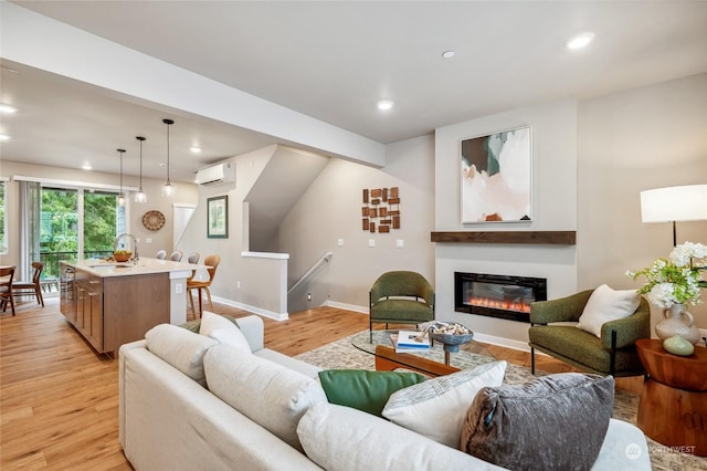 living room with sink, light hardwood / wood-style flooring, and an AC wall unit