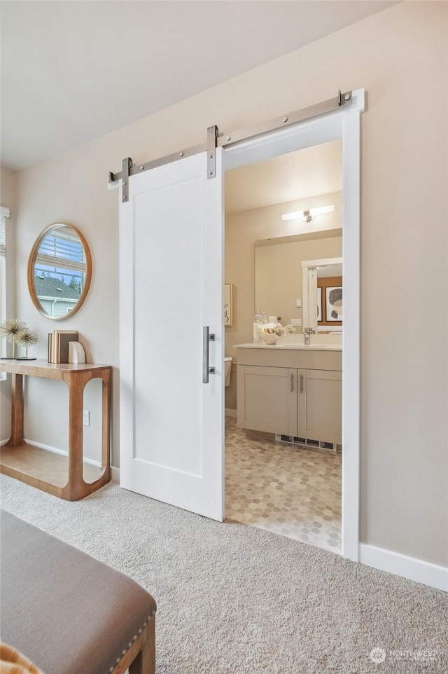 hall with light colored carpet and a barn door