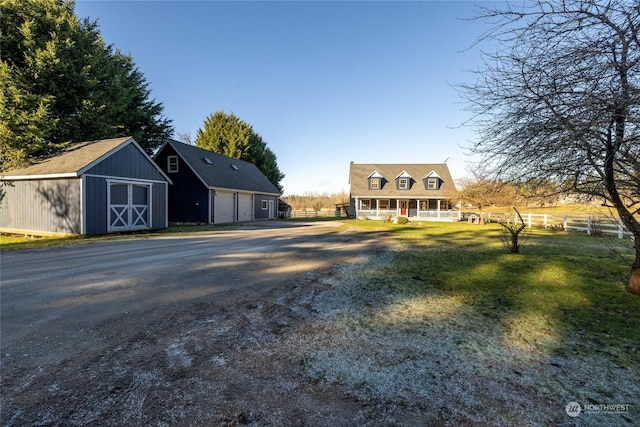 new england style home featuring a garage, a front yard, a porch, and a storage unit