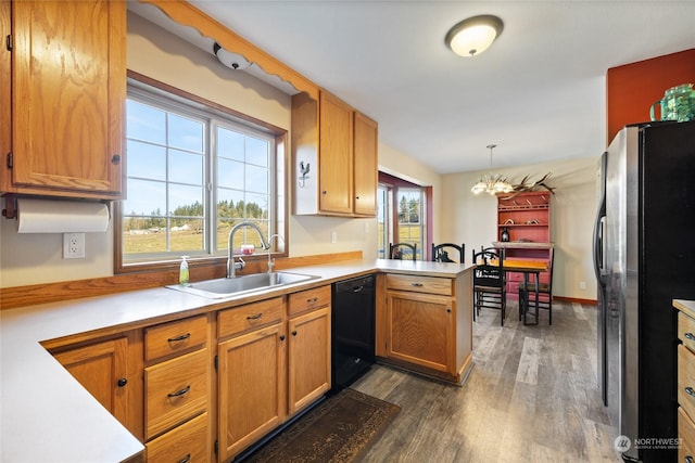 kitchen featuring stainless steel refrigerator, decorative light fixtures, black dishwasher, sink, and kitchen peninsula