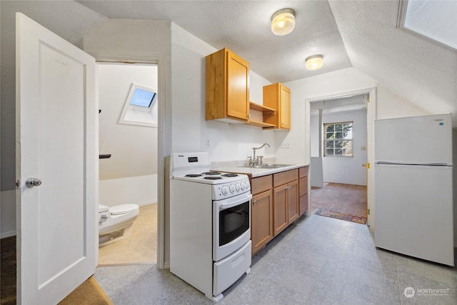 kitchen with sink, white appliances, vaulted ceiling, and a textured ceiling