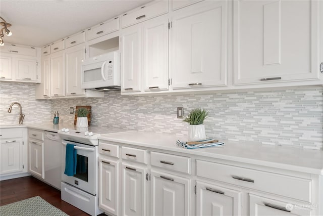 kitchen with sink, white cabinetry, dark hardwood / wood-style floors, white appliances, and backsplash