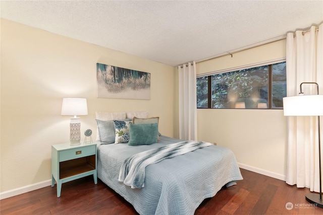 bedroom with dark hardwood / wood-style floors and a textured ceiling