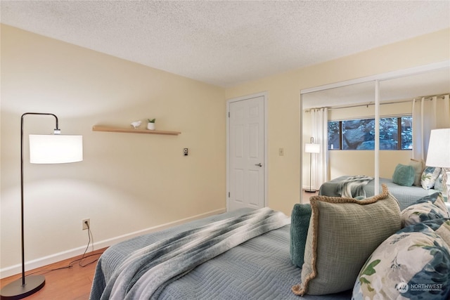 bedroom with hardwood / wood-style flooring, access to outside, and a textured ceiling