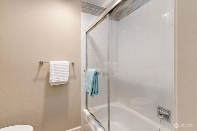 bathroom with combined bath / shower with glass door and toilet