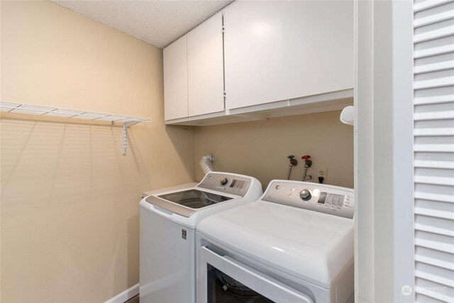 washroom with washing machine and dryer, cabinets, and a textured ceiling