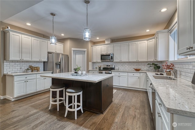 kitchen featuring sink, hanging light fixtures, appliances with stainless steel finishes, a kitchen island, and white cabinets