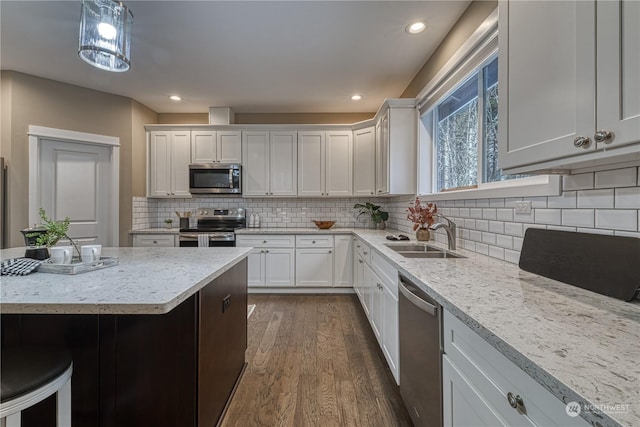 kitchen featuring dark hardwood / wood-style floors, sink, white cabinets, hanging light fixtures, and stainless steel appliances