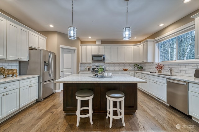 kitchen featuring pendant lighting, stainless steel appliances, a center island, and white cabinets