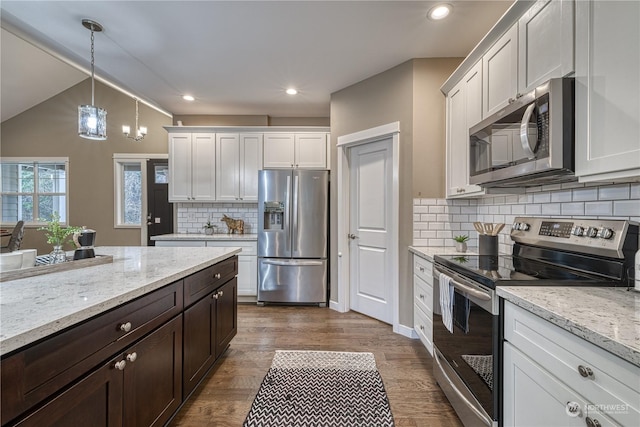 kitchen with white cabinetry, light stone counters, pendant lighting, and appliances with stainless steel finishes