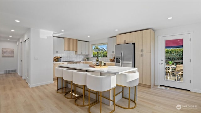 kitchen with stainless steel refrigerator with ice dispenser, a breakfast bar area, and a kitchen island