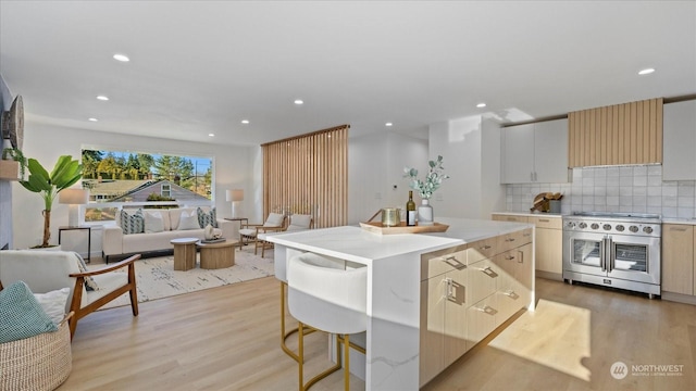 kitchen with high end range, light hardwood / wood-style flooring, a center island, and wall chimney exhaust hood