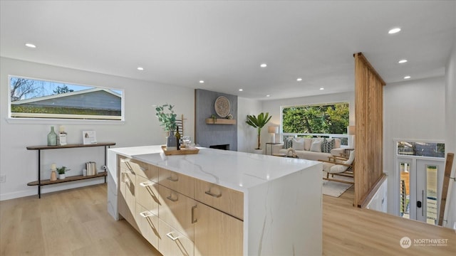 kitchen with a kitchen island, light stone counters, and light hardwood / wood-style floors