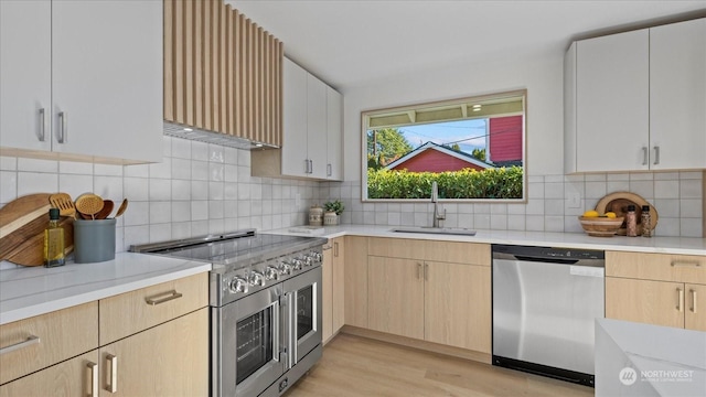 kitchen featuring sink, light brown cabinets, stainless steel appliances, light hardwood / wood-style floors, and backsplash