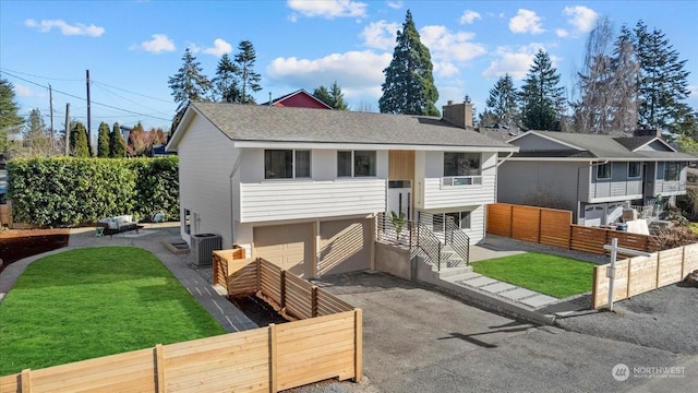 bi-level home featuring central AC unit, a garage, and a front yard