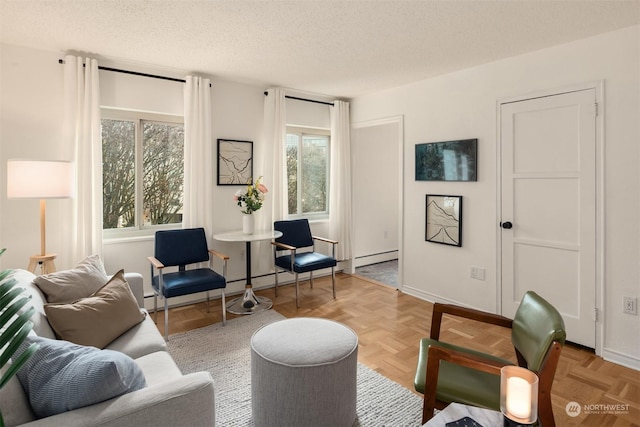 living area featuring light parquet flooring, a textured ceiling, and a baseboard heating unit