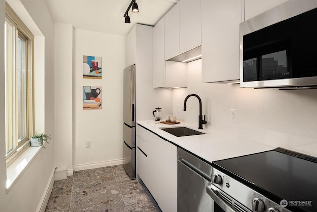 kitchen with stainless steel appliances, white cabinetry, rail lighting, and sink